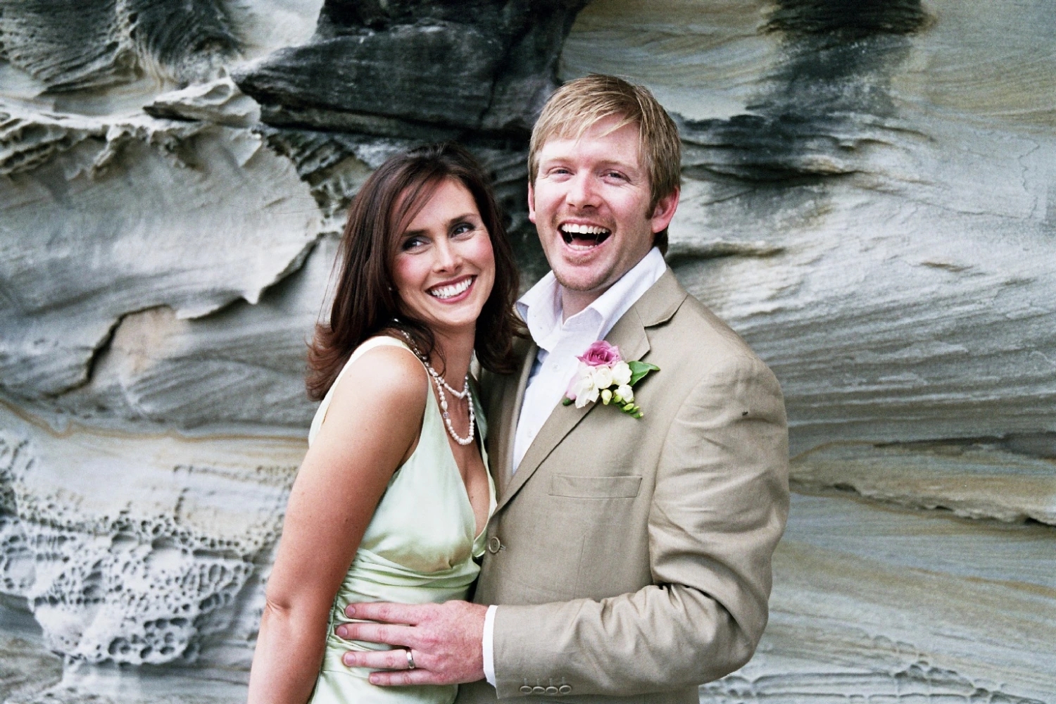 Sarhn - Bride and groom share a laugh at the beach beside the rocks photograph